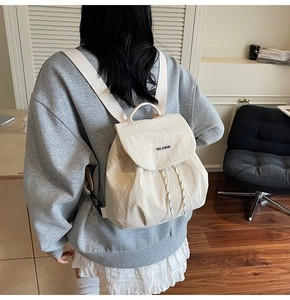 Rear view of a model wearing the cream white canvas backpack for daily commuting