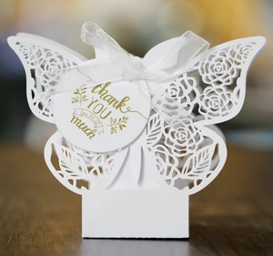 Détail macro d'une boîte cadeau papillon ajourée blanche avec ruban et étiquette merci