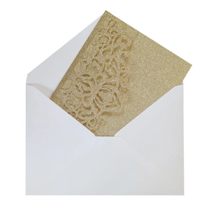 Macro detail of laser-cut gold glitter wedding invitation with matching white envelope