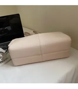 Detailed view of beige leather bag base with cross stitching and lychee texture