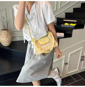 Detail of yellow and white checkered crossbody bag with unique braided handle