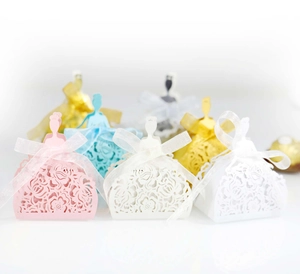 Detail of laser-cut wedding favor boxes in dress shapes with elegant organza ribbons
