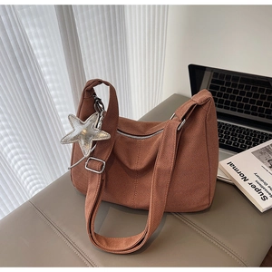 Detailed close-up of brown knitted tote bag texture with silver star charm and strap