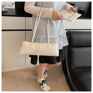 Detail of woven texture on minimalist cream underarm bag with slim shoulder straps