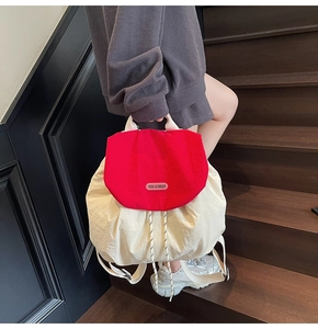 Detailed view of dual-color casual backpack with red flap and cream nylon body fabric