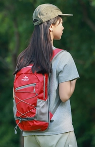 Lightweight red outdoor hiking backpack on female model with natural forest background