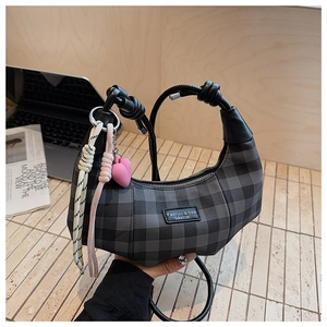 Detail of grey checkerboard crescent bag with heart charm and leather knotted handle