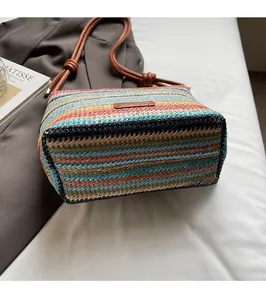 Détail du sac à bandoulière tissé à rayures colorées avec des anses en cuir marron