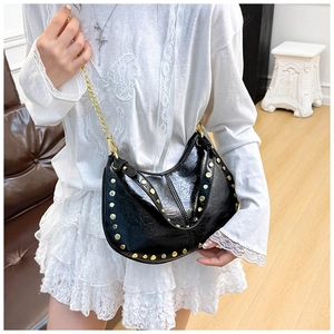 Detail of black leather hobo bag featuring golden rivets and adjustable chain strap