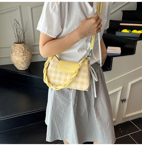 Detail showing yellow and cream plaid mini square bag with braided handle on stairs