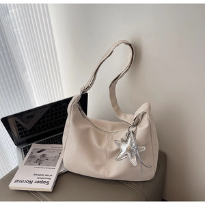 Detail of beige half-moon bag with woven texture, silver star charm, and wide strap