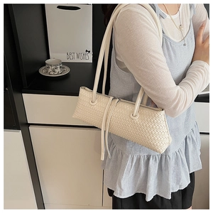 Macro detail of cream woven baguette bag featuring long zippers and leather texture