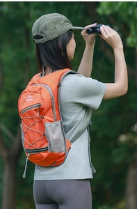 Detail of orange nylon hiking backpack with elastic cord system and side mesh bottle pocket