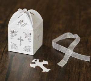Detailed laser-cut white favor box with cross pattern, rose motifs and silk ribbon