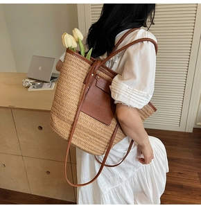 Detail of straw tote bag showing brown faux leather pockets and woven texture