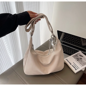 Close-up of beige crescent bag with textured herringbone fabric and silver pendant detail