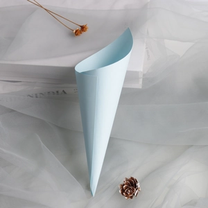 Close-up of light blue paper confetti cone placed on white mesh fabric for wedding decor