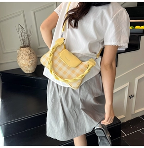 Detail view of yellow plaid crossbody bag with a distinctive braided handle and leather flap