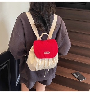 Detail view of small red and cream canvas drawstring backpack with YOU JI BEAR label