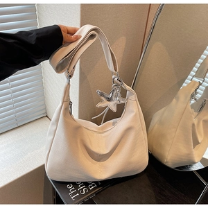 Detailed view of the white herringbone knit hobo bag with a shiny silver star pendant