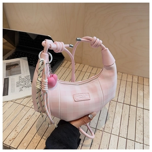 Detailed view of pink crescent bag with checkered pattern and heart-shaped pendant detail