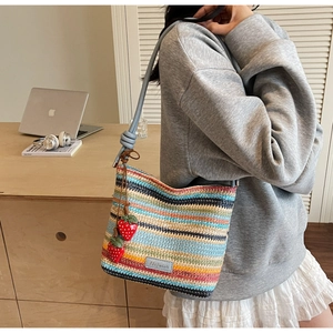 Détail du sac seau tissé coloré avec breloques fraises et bandoulière en cuir