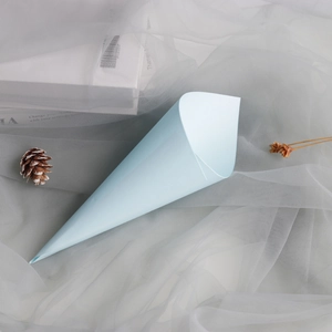 Close-up of light blue lace paper cone for wedding confetti placed on soft fabric