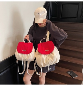 Detail of red and white contrasting drawstring backpacks in two sizes with metal logos