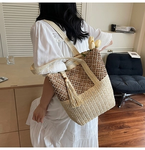 Detailed close-up of a woven straw tote bag with dual-tone texture and stylish beige tassels
