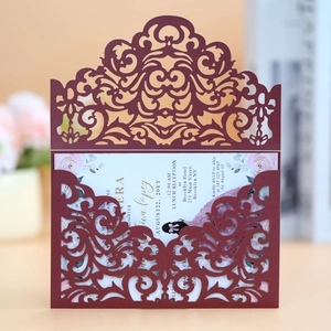 Detail of laser-cut burgundy wedding invitation with elegant floral insert and text