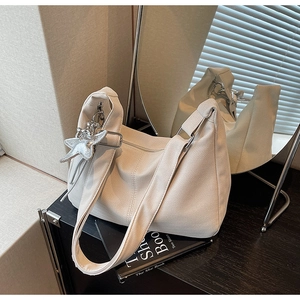 Detailed texture of a cream hobo bag with wave pattern and silver star pendant charm