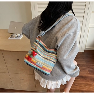 Détail du sac seau en paille tissée colorée avec charms fraises et bandoulière en corde bleue