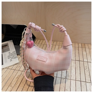 Detailed view of pink checkered crescent bag with woven handle and heart charm