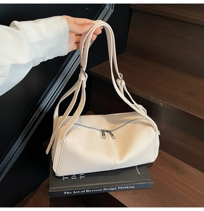 Dettaglio borsa pillow in pelle beige con doppia cerniera argentata e tracolla sottile
