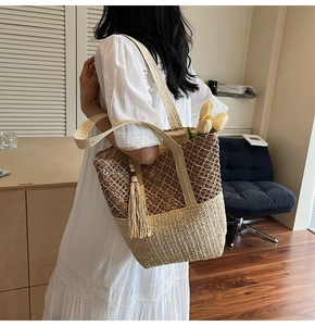 Detail of a woven straw tote with wooden bead tassels shown on a model in a resort setting