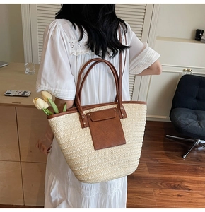 Detailed view of large straw tote with brown leather trim and front pocket design
