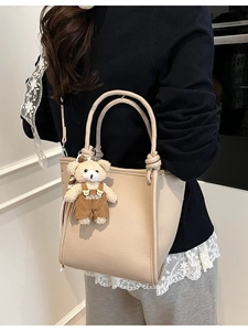 Chic beige lychee grain leather bucket bag with cute bear charm for summer casual wear