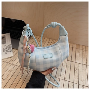 Detail of light blue plaid crescent bag with leather label and colorful heart pendant