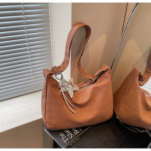 Detail of terracotta herringbone fabric shoulder bag with silver starfish charm and strap