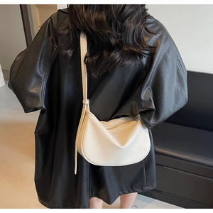 Fashionable cream white moon hobo bag with pebble leather texture on a black jacket