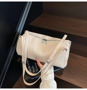 Detail view of cream beige boston bag with pebble grain texture and dual metal zippers