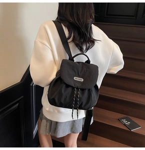 Black nylon drawstring backpack shown from behind on a model at a wooden staircase