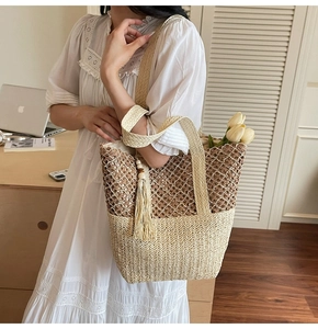 Detailed close-up of two-tone woven tote bag with fringe charm and hollow mesh texture
