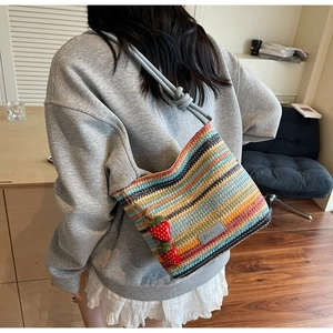 Détail du sac seau tissé arc-en-ciel avec un joli pendentif fraise en relief