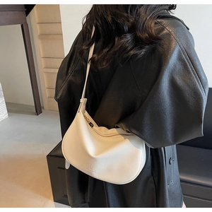 Detail of white pebbled leather crescent bag with gold zipper worn with a black jacket