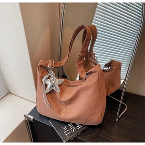Detail of caramel brown canvas hobo bag featuring wave texture and star pendant