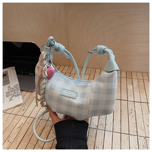 Detail of blue plaid crescent handbag featuring heart charm and fashion label