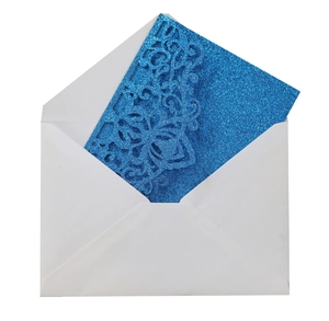 Macro view of blue glitter wedding invitation card with laser-cut lace and white envelope