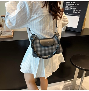 Detail of grey plaid crossbody bag with a braided shoulder strap worn by a model