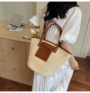 Macro shot of large capacity woven straw tote with brown leather pockets and long handles